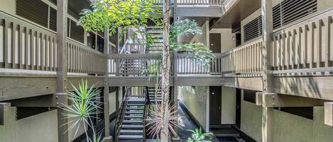 A multi-level atrium with a central staircase, surrounded by balconies and vegetation.