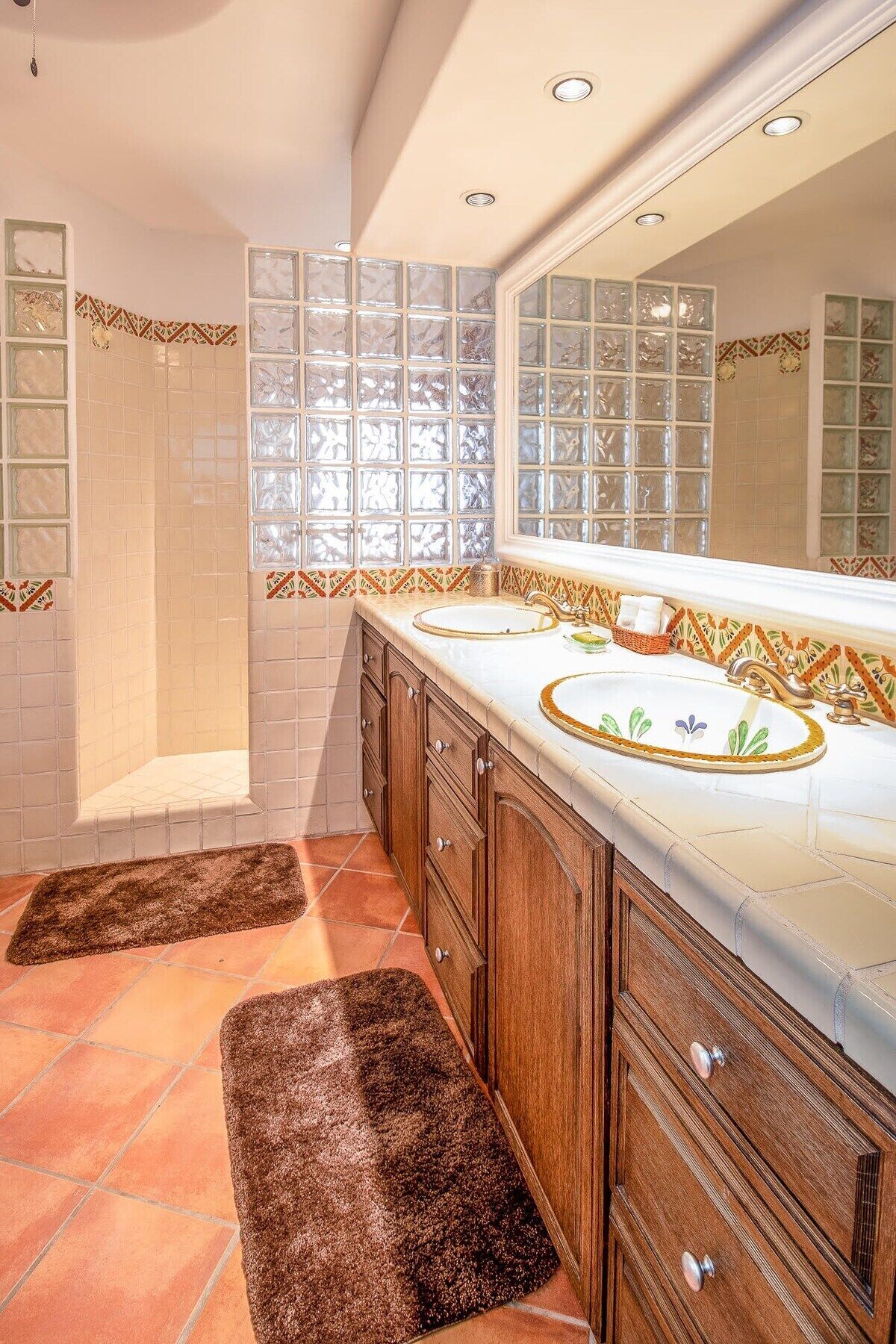 A bathroom with a large mirror, two sinks, and a shower.