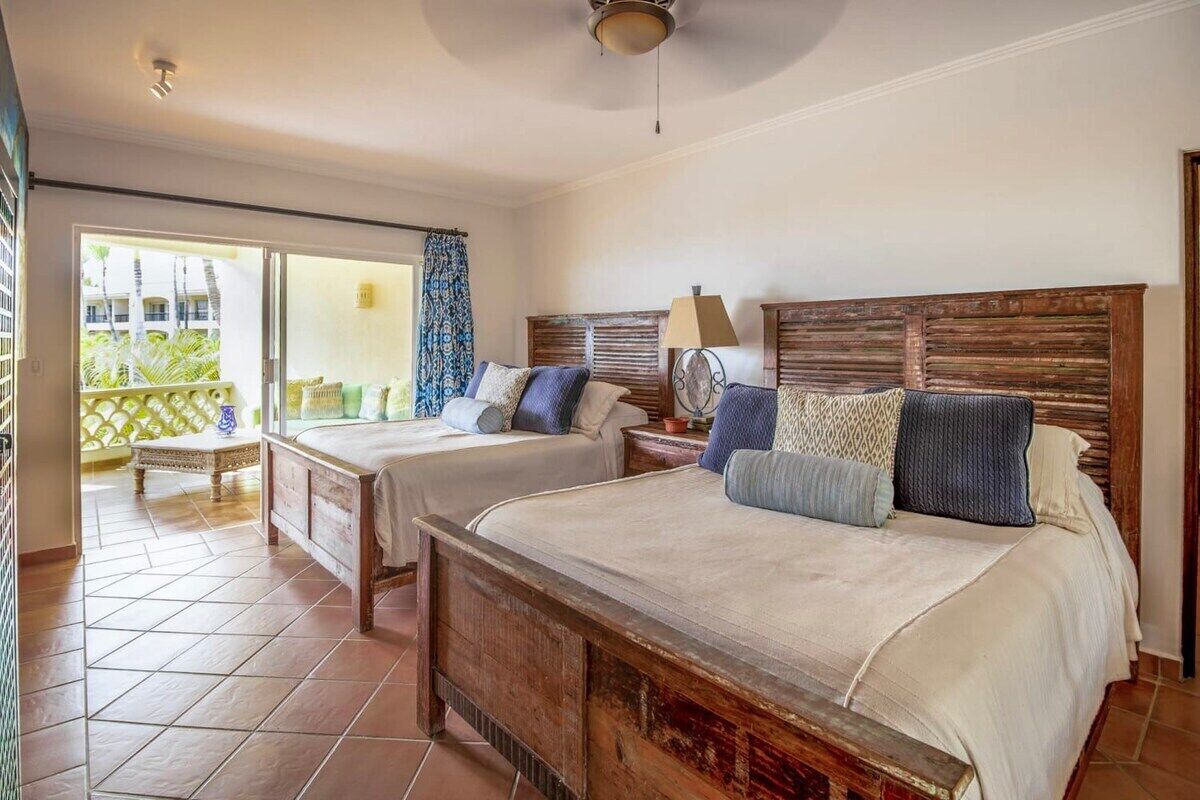 Ein Schlafzimmer mit zwei Betten, einem Balkon und Blick auf Palmen.