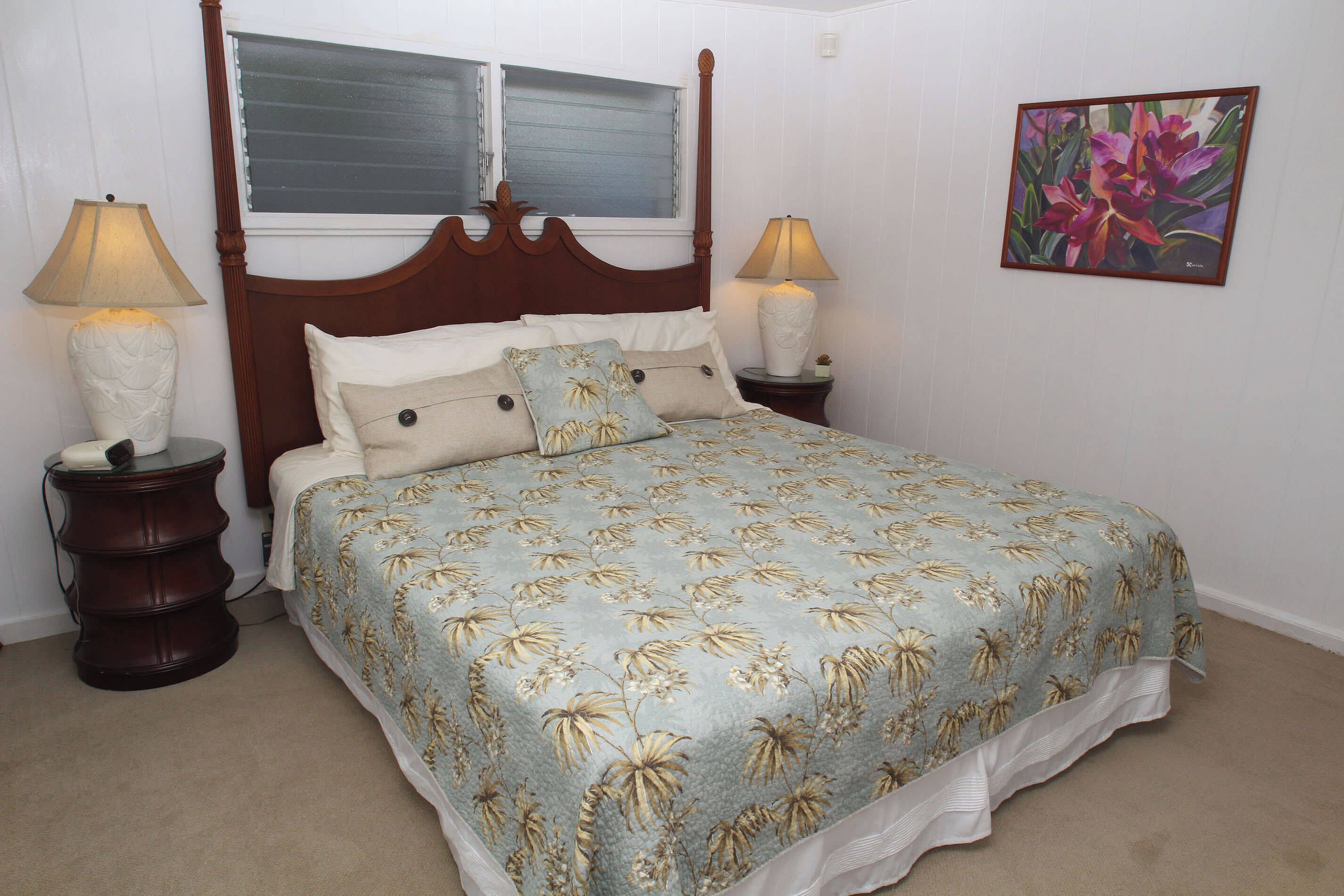 Ein Schlafzimmer mit einem Himmelbett, zwei Nachttischen, einem Fenster mit Jalousien und einem Blumenbild an der Wand.
