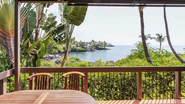 A wooden deck with a table and chairs, overlooking a tropical beach with palm trees and a clear view of the ocean. - Kanaloa At Kona Enjoy Peace in Paradise! (Kailua-Kona)