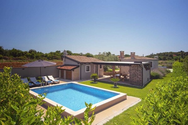 A modern house with a swimming pool, a patio, and a garden.