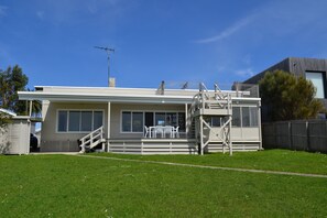 Ein zweistöckiges Haus mit einer überdachten Terrasse und einem eingezäunten Garten.