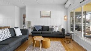 Un salon moderne avec un canapé gris, une table basse en bois et une grande fenêtre donnant sur un beau paysage.