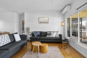 Ein modernes Wohnzimmer mit einem grauen Sofa, einem Holztisch und einem großen Fenster mit Blick.