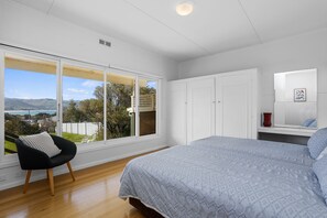 Ein Schlafzimmer mit großem Fenster, einem Bett, einem Kleiderschrank und einem Sessel.