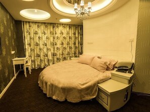A bedroom with a bed, bedside table, and a nightstand with a phone. - Greentree Inn Nantong Haimen Sanchang North Wangjiang Road Business Hotel (Nantong)