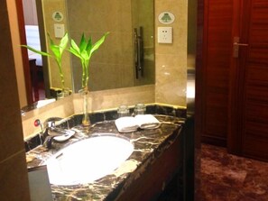 A bathroom with a marble sink, a mirror, a green plant, and a towel on the counter. - Greentree Inn Nantong Haimen Sanchang North Wangjiang Road Business Hotel (Nantong)