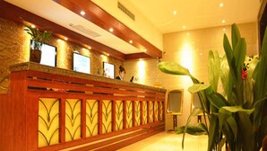 A reception area with a wooden reception desk, potted plants, and a tiled wall. - Greentree Inn Nantong Haimen Sanchang North Wangjiang Road Business Hotel (Nantong)