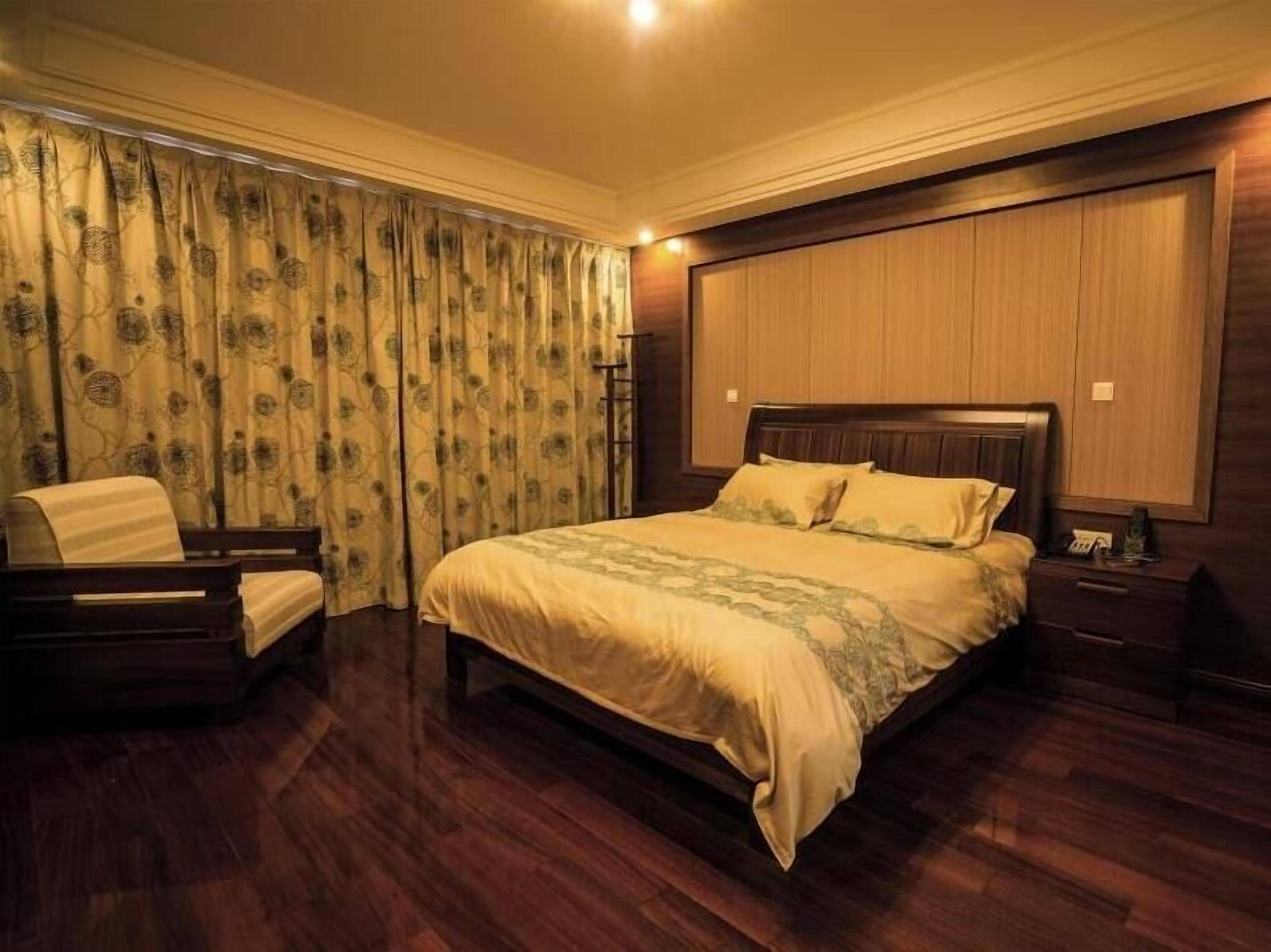 Un dormitorio con una cama grande, una silla, una mesita de noche y un armario.