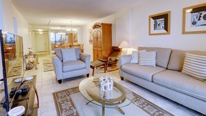 A living room with two sofas, a coffee table, and a dining area with chairs and a table. - St Pete Beach Yacht and Tennis Club 90 Day Rental Gated With Pool (St. Pete Beach)