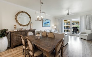 A spacious living room with a dining area, a large mirror, and a ceiling fan.