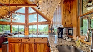 A spacious kitchen with wooden cabinets, granite countertops, and large windows offering a view of the outdoors. - Hot Tub, 3 Fireplaces, Mountain Views, Game Room (Blue Ridge)