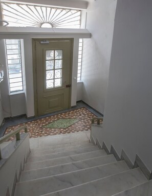 A staircase leading to a door with a decorative glass panel, a patterned floor, and a skylight above. - Lux 2BR Home On The Steps Of Acropolis (Athens)