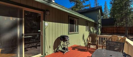 A covered patio with outdoor seating, a bicycle, and a sign on the door.