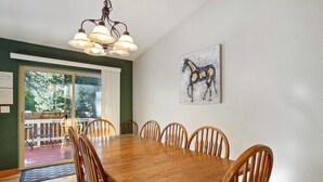 A dining area with a wooden table and chairs, a chandelier, and a horse painting on the wall.