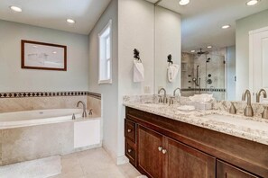 Un baño moderno con una bañera grande, un lavabo doble con encimera de mármol y un espejo amplio.