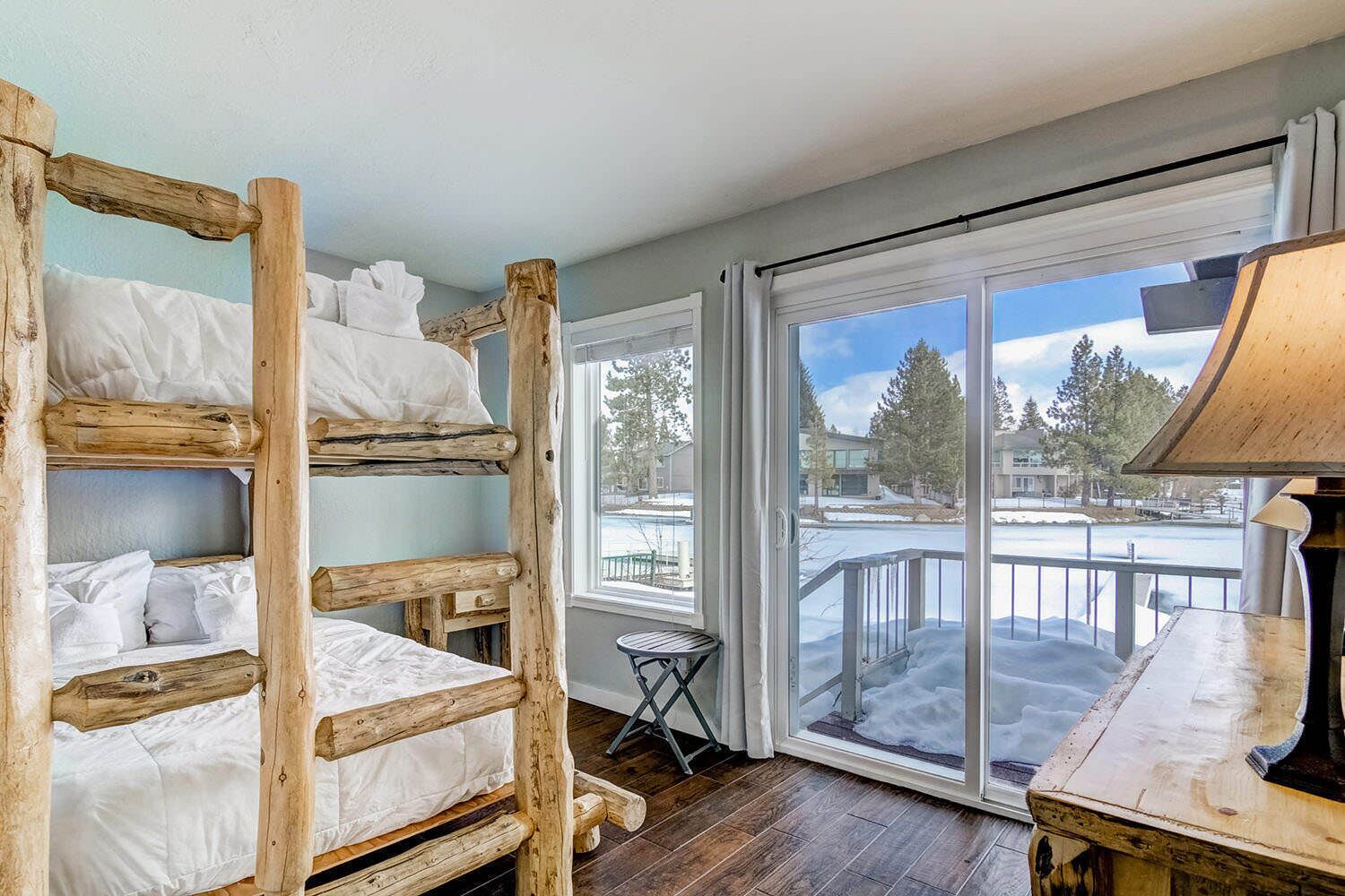 Ein Zimmer mit Etagenbetten, einem kleinen Tisch und Blick auf eine verschneite Landschaft.