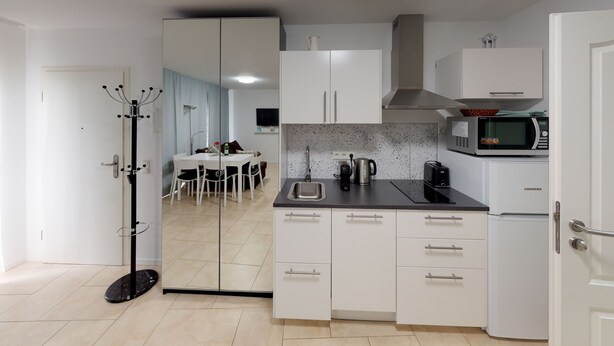 A modern kitchen with white cabinets, a stainless steel sink, a microwave, and a coffee maker. - Studio Apartment , 33m2 (Bad Homburg vor der Höhe)