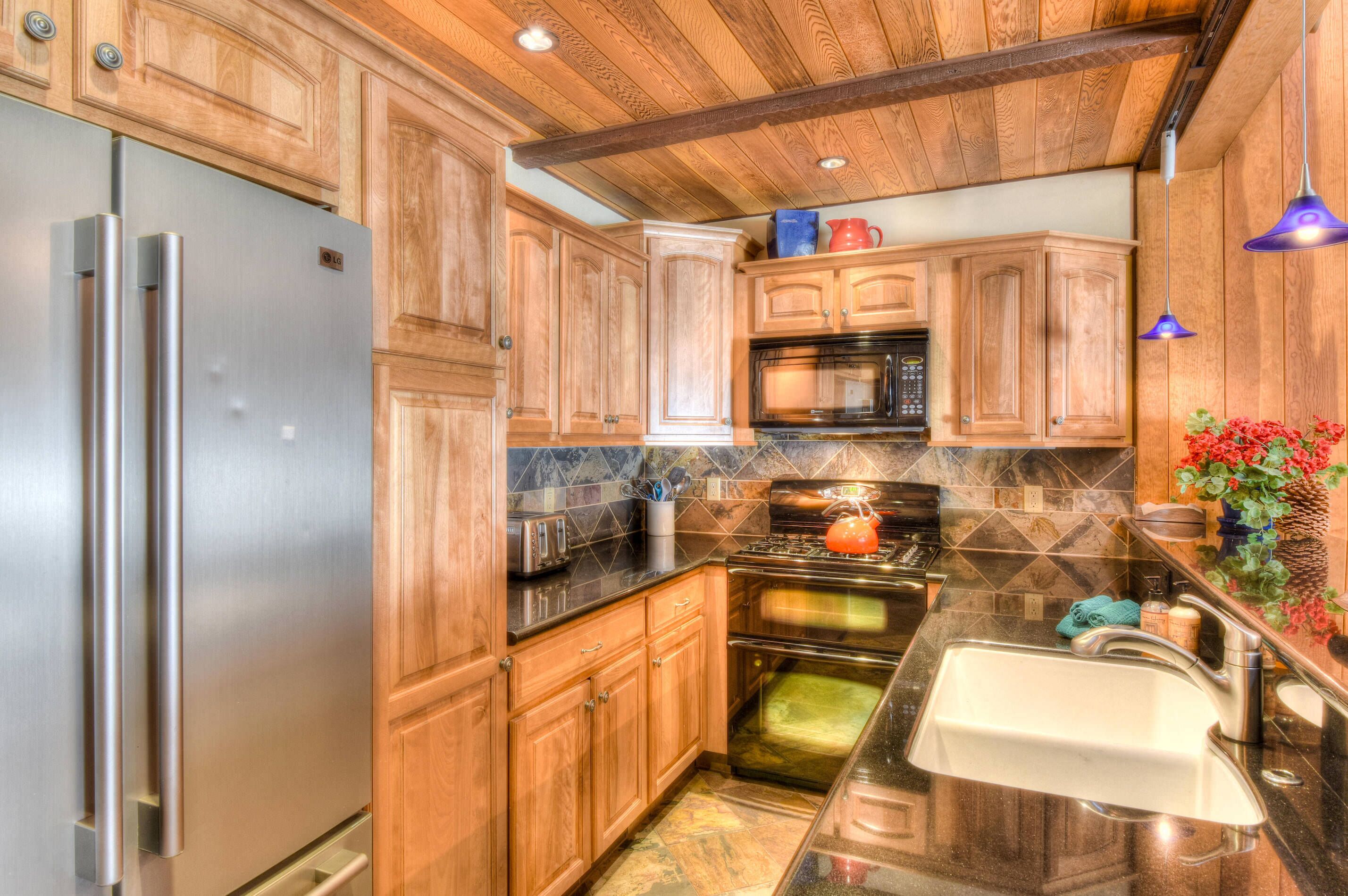A kitchen with wooden cabinets, stainless steel appliances, a granite countertop, and a sink.