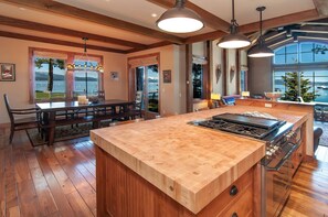 Une cuisine spacieuse dotée d’un grand îlot central, d’un plancher en bois et offrant une vue sur l’extérieur.