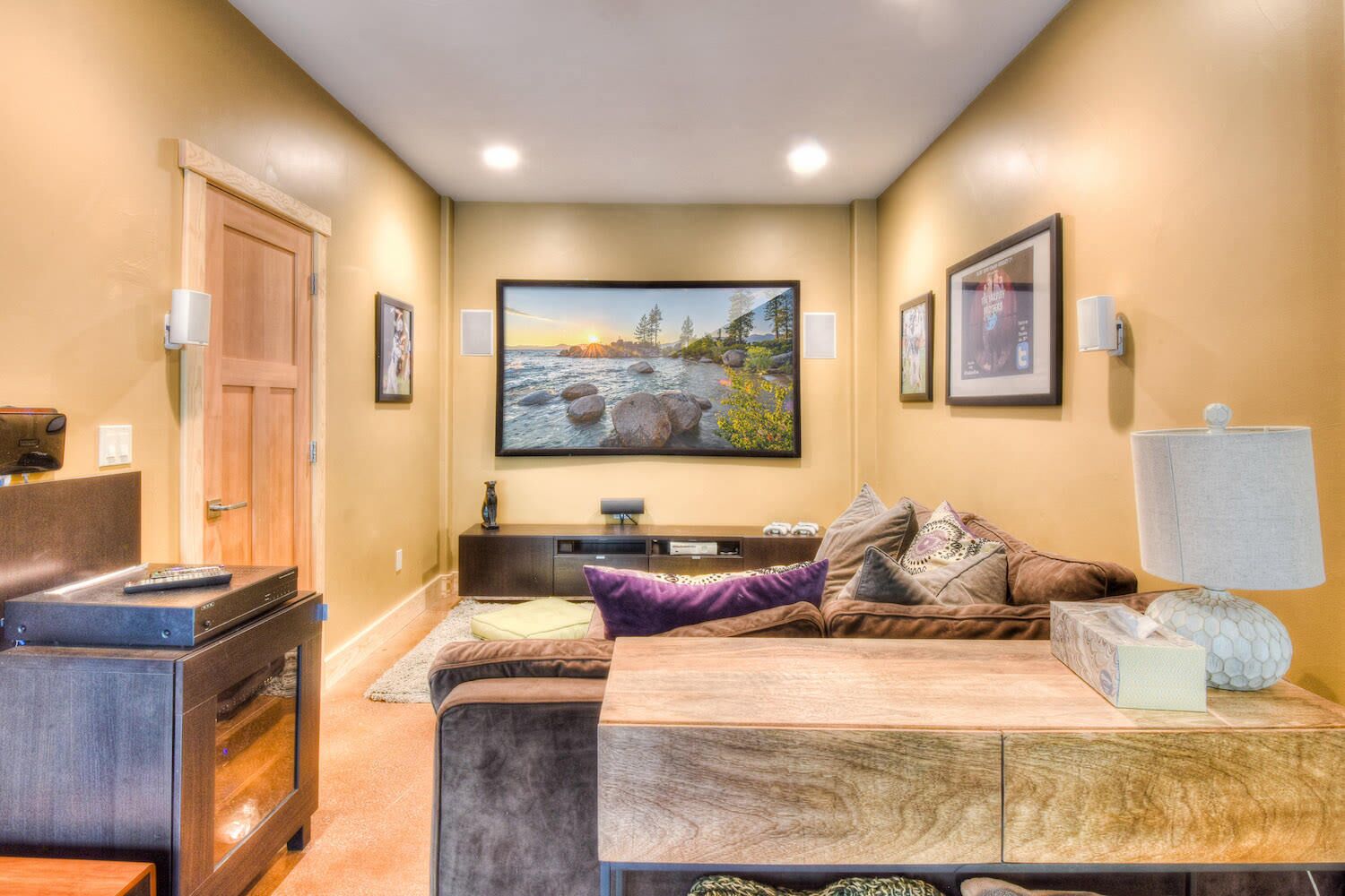 A living room with a large flat-screen TV, a sofa, a coffee table, and a fireplace.