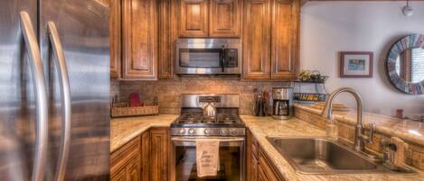 A modern kitchen with wooden cabinets, stainless steel appliances, granite countertops, and a built-in oven.