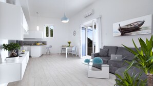 A modern living room with a grey sofa, a glass coffee table, and a dining area with a white table and chairs. - Villa Anna with private Terrace and Sea View (Positano)