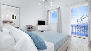 A bedroom with a bed, a TV, a window with curtains, and a balcony with a railing. - Villa Anna with private Terrace and Sea View (Positano)
