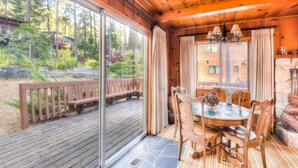 A wooden cabin with a dining area, large windows, and a deck.