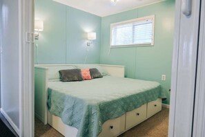 Un dormitorio con cama, lámparas de noche, una ventana y una puerta.