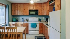 Une cuisine avec des meubles en bois, un four blanc, un four à micro-ondes et un réfrigérateur.