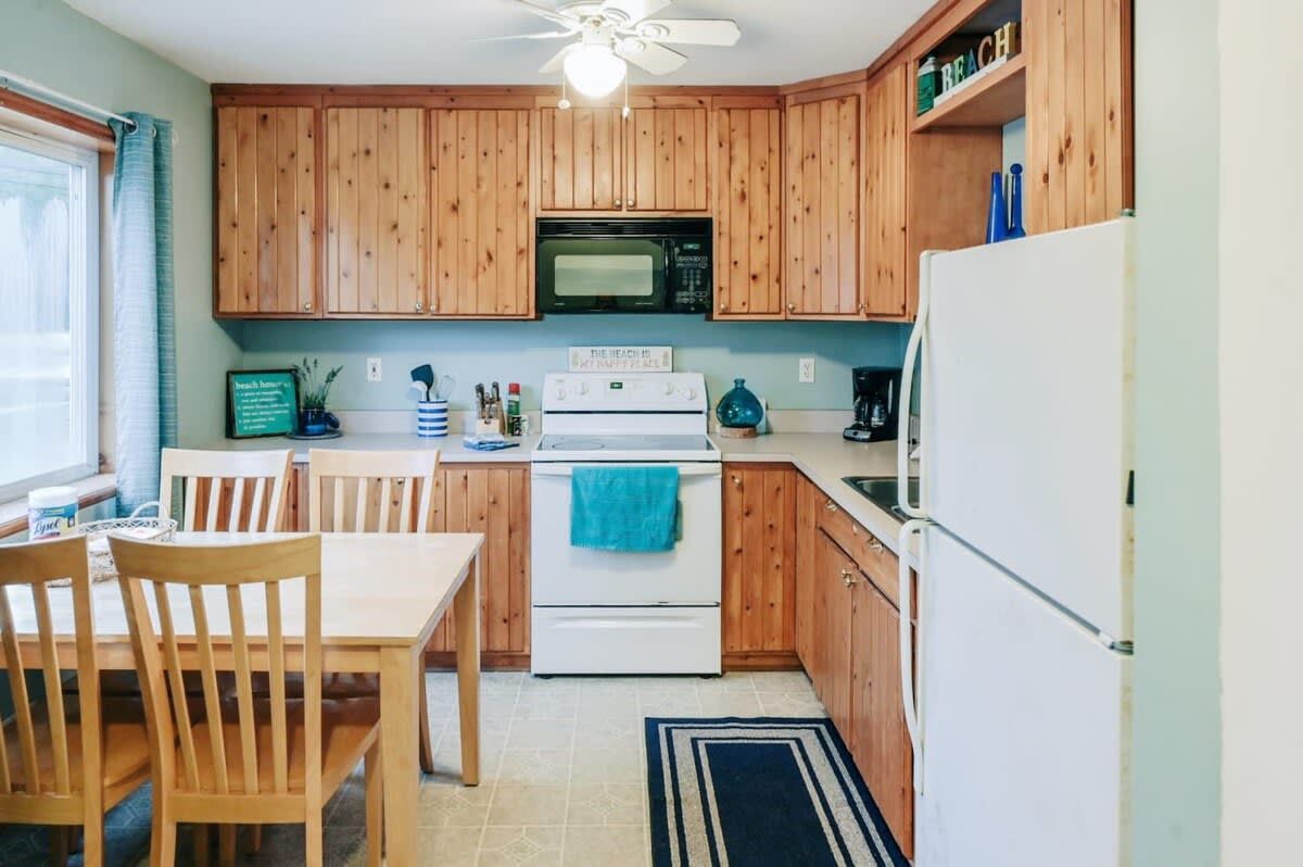 Una cocina con armarios de madera, estufa blanca, microondas y refrigerador.