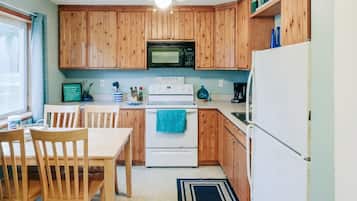 Una cocina con armarios de madera, estufa blanca, microondas y refrigerador.