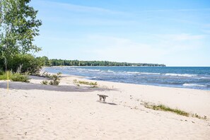Ein Sandstrand mit einer Bank und einem kleinen Gebäude, wahrscheinlich einer Rettungswache, in der Nähe des Wassers.