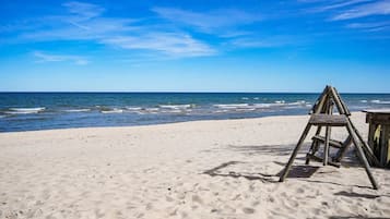 A beach with a wooden ladder and a small wooden structure, likely a table or bench, on the sand.
