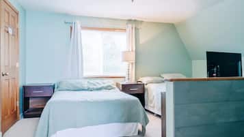 A bedroom with a bed, bedside tables, a lamp, a TV, and a window with curtains.