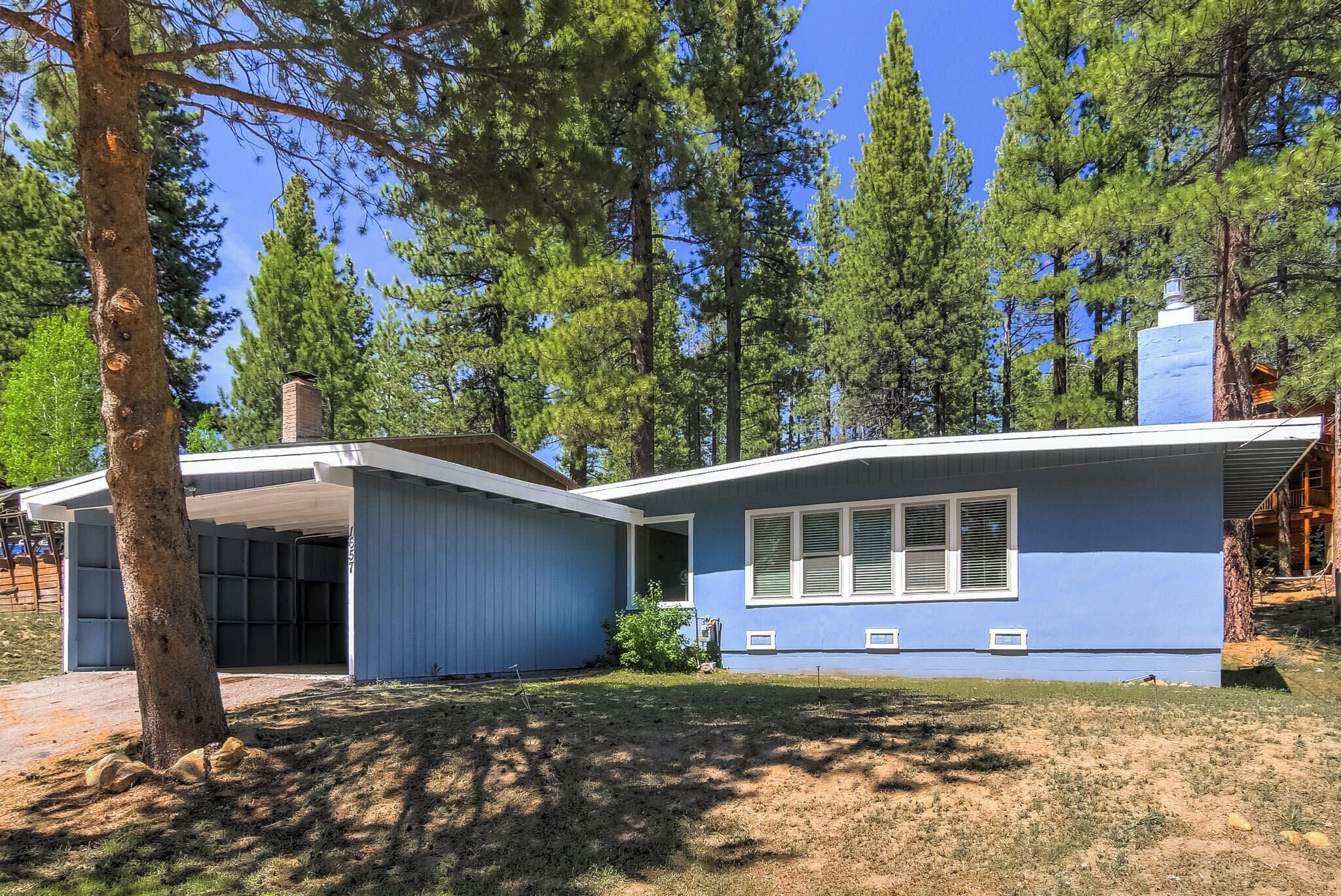 A single-story house with a blue exterior, a covered porch, and a chimney.