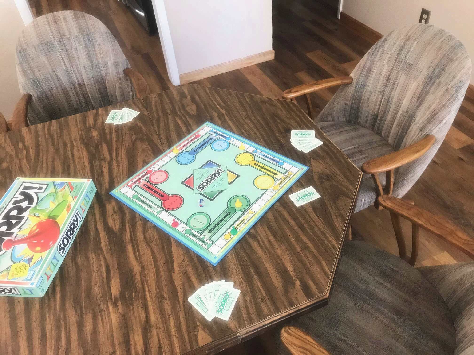 A board game on a wooden table surrounded by four chairs.