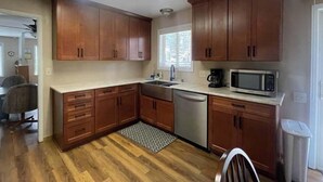 A kitchen with wooden cabinets, a dishwasher, a microwave, and a window with blinds.