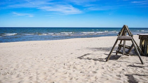 A beach with a wooden ladder and a small wooden structure, likely a table or bench, on the sand. - Stunning views of Lake Huron (Oscoda)
