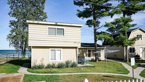 A two-story house with a front yard, a wooden deck, and a white picket fence. - Stunning views of Lake Huron (Oscoda)