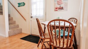 A dining area with a wooden table and chairs, a staircase with a 'To the Lake' sign, and a window with curtains. - Stunning views of Lake Huron (Oscoda)