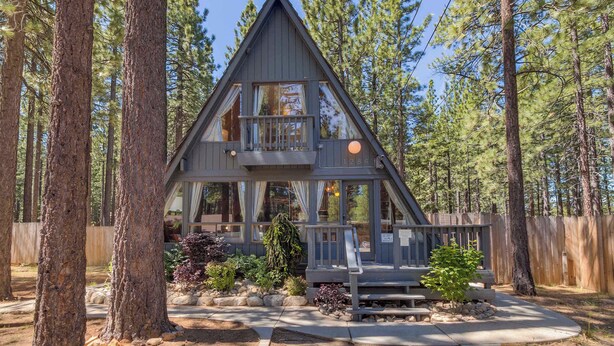 A cabin with a balcony, surrounded by trees.