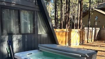 Un jacuzzi en un patio trasero con terraza de madera y valla de madera.