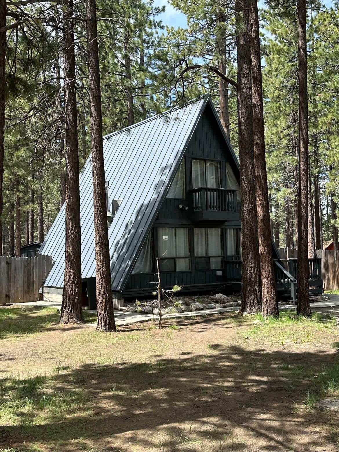 A cabin with a sloped roof, surrounded by tall pine trees.