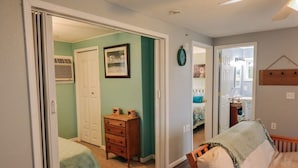 A bedroom with a bed, a dresser, and a door leading to another room.