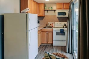 Una cocina compacta con armarios de madera, un refrigerador blanco, un microondas y una estufa.