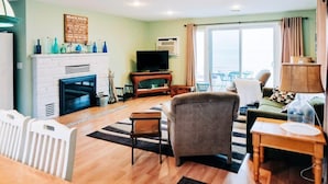 A living room with a fireplace, television, and a view of the outdoors. - Beachfront cottage on Lake Huron (Oscoda)