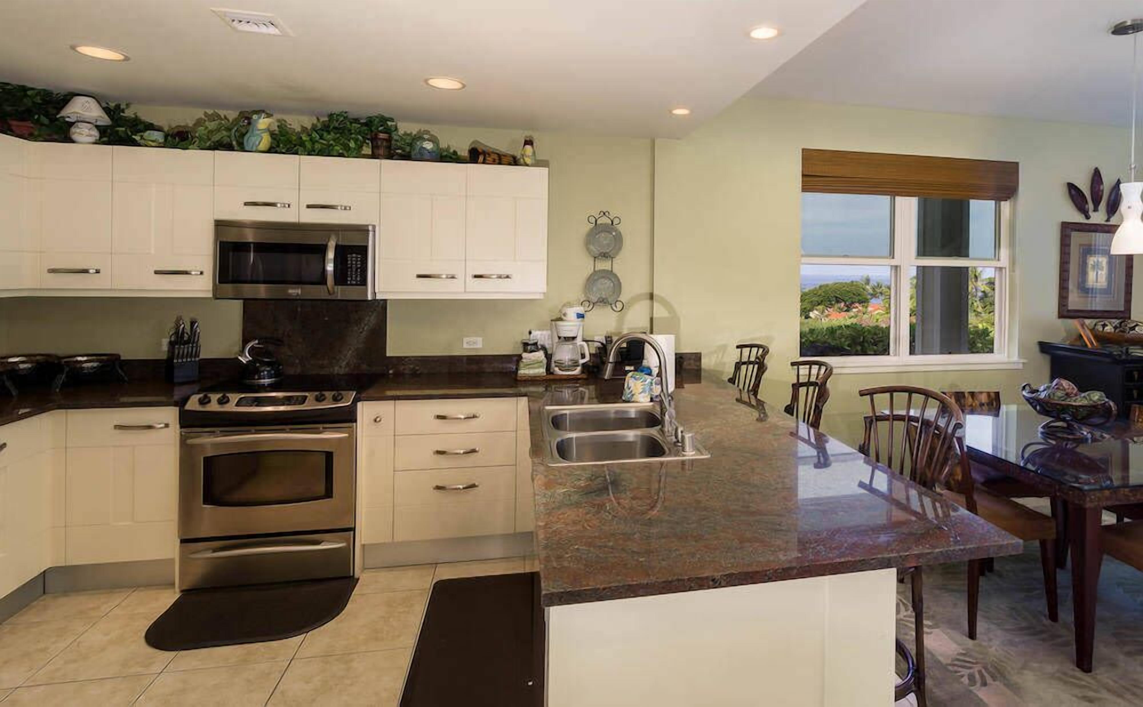 Una cocina moderna con electrodomésticos de acero inoxidable, una isla grande con un lavamanos y un comedor con sillas de madera.